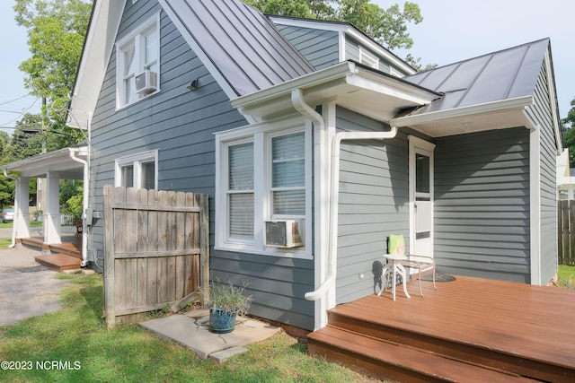 view of side of home with cooling unit, a standing seam roof, fence, and metal roof