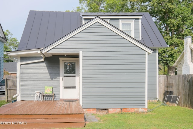 rear view of property featuring crawl space, fence, a wooden deck, and a lawn