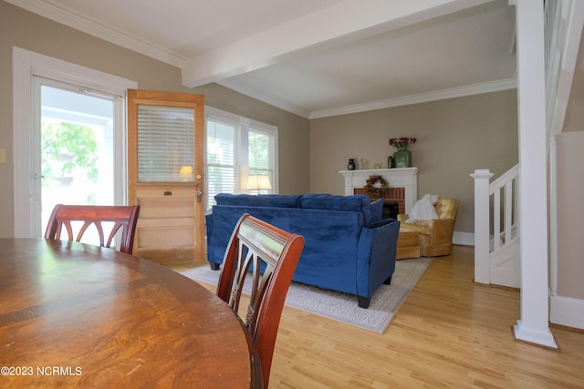 dining space with light wood-style floors, a healthy amount of sunlight, beamed ceiling, and stairs