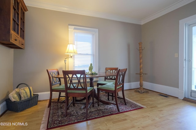 dining area with ornamental molding, light wood-style flooring, and baseboards