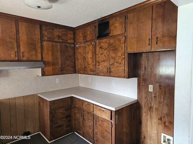 kitchen with a textured ceiling and wall chimney exhaust hood