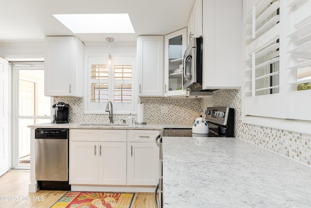 404 Mercer St, Oak Island, NC 28465 - kitchen featuring stainless steel appliances, a skylight, white cabinets, and light wood finished floors