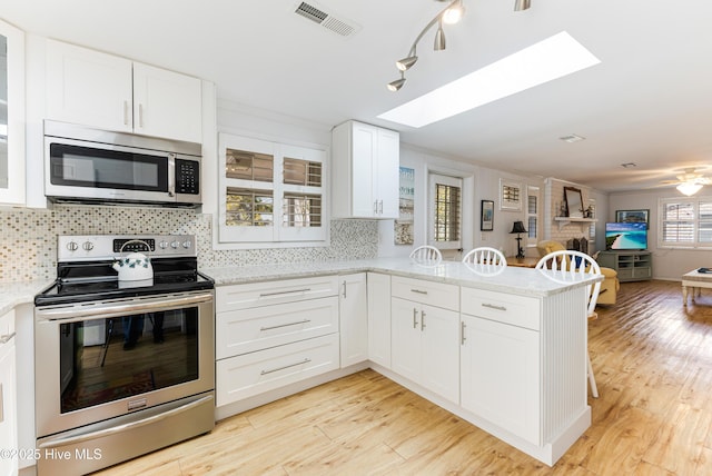 404 Mercer St, Oak Island, NC 28465 - kitchen with stainless steel appliances, a peninsula, open floor plan, and white cabinets