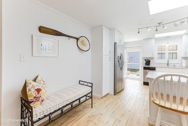 404 Mercer St, Oak Island, NC 28465 - kitchen with stainless steel appliances, a skylight, light wood-style floors, decorative backsplash, and white cabinets