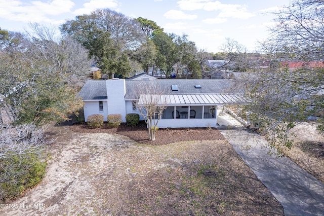 404 Mercer St, Oak Island, NC 28465 - view of front of house featuring a sunroom, a standing seam roof, a metal roof, and driveway