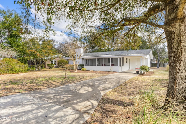 404 Mercer St, Oak Island, NC 28465 - ranch-style house with concrete driveway, a sunroom, an attached carport, and roof with shingles
