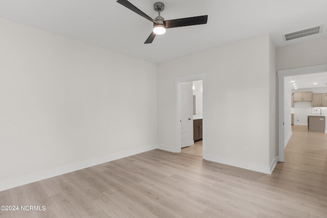 unfurnished room with sink, ceiling fan, and light wood-type flooring