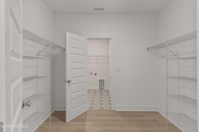 walk in closet with light hardwood / wood-style flooring