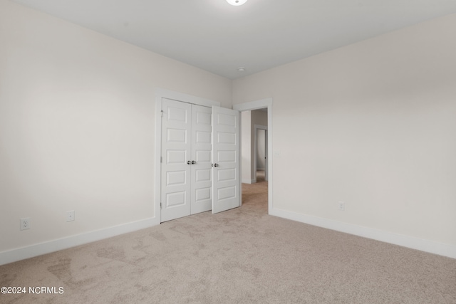 unfurnished bedroom featuring light carpet and a closet