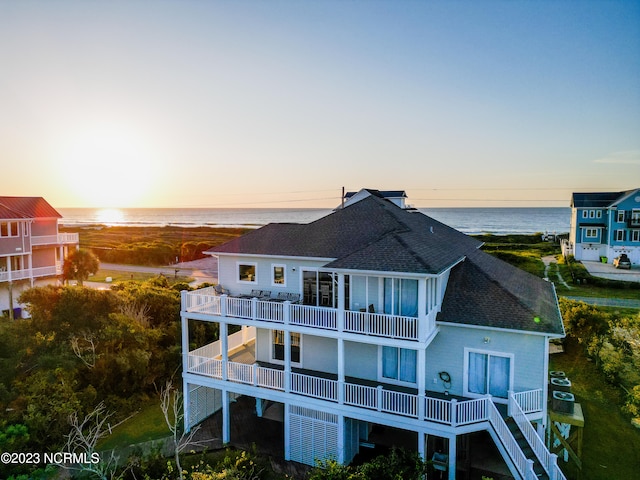 back house at dusk with a balcony and a water view