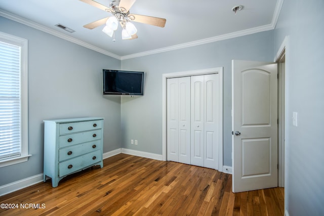 unfurnished bedroom with dark hardwood / wood-style floors, a closet, ornamental molding, and ceiling fan