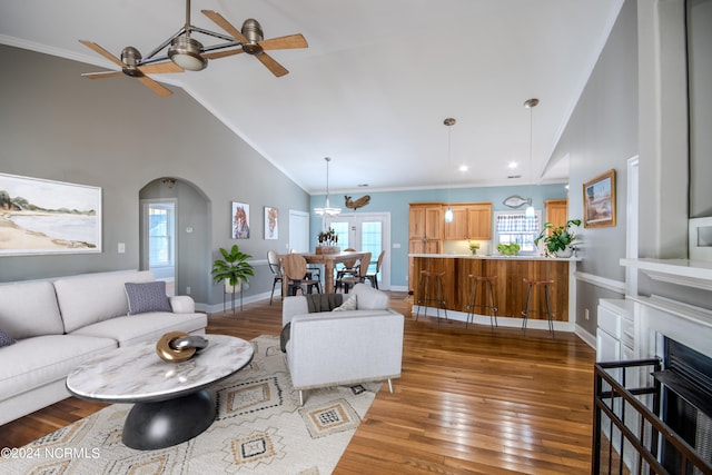 living room featuring ceiling fan, dark hardwood / wood-style flooring, high vaulted ceiling, and ornamental molding