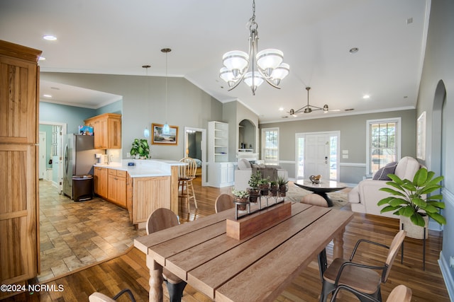 dining area with ceiling fan with notable chandelier, lofted ceiling, crown molding, and light hardwood / wood-style flooring