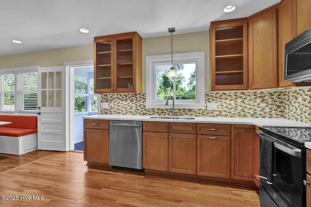 kitchen featuring appliances with stainless steel finishes, a sink, brown cabinetry, light countertops, and recessed lighting