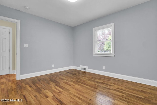 spare room with wood finished floors, baseboards, and a smoke detector