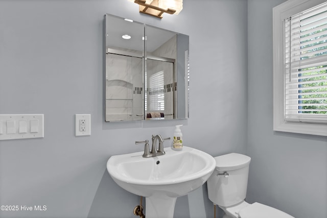 bathroom featuring a stall shower, toilet, and a sink