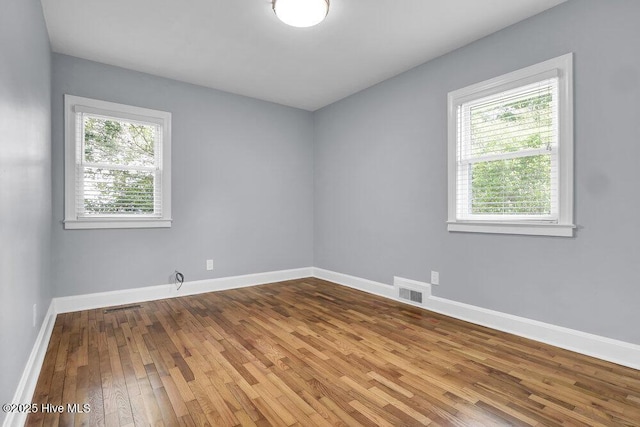 empty room with hardwood / wood-style floors and baseboards