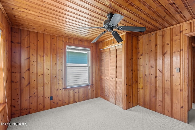 spare room with carpet flooring, wood walls, ceiling fan, and wooden ceiling