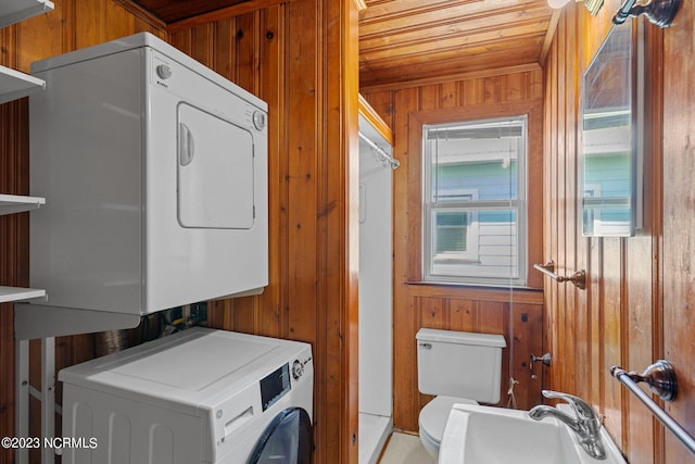 clothes washing area featuring wooden walls, wooden ceiling, and stacked washing maching and dryer