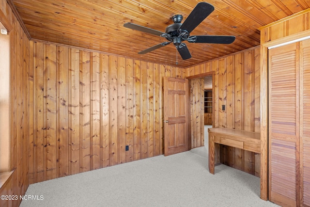 empty room with light carpet, wood ceiling, wooden walls, and ceiling fan