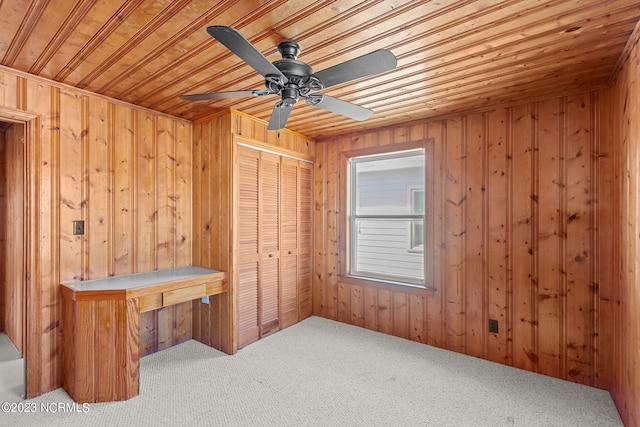 interior space with wooden walls, wood ceiling, ceiling fan, and carpet floors