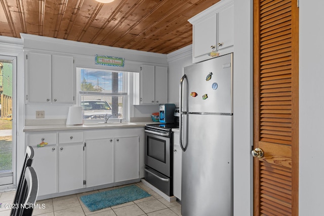 kitchen with appliances with stainless steel finishes, sink, light tile flooring, and white cabinets