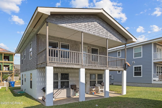 rear view of property featuring a lawn, a balcony, and a patio area