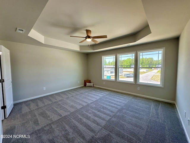 carpeted empty room featuring a tray ceiling and ceiling fan