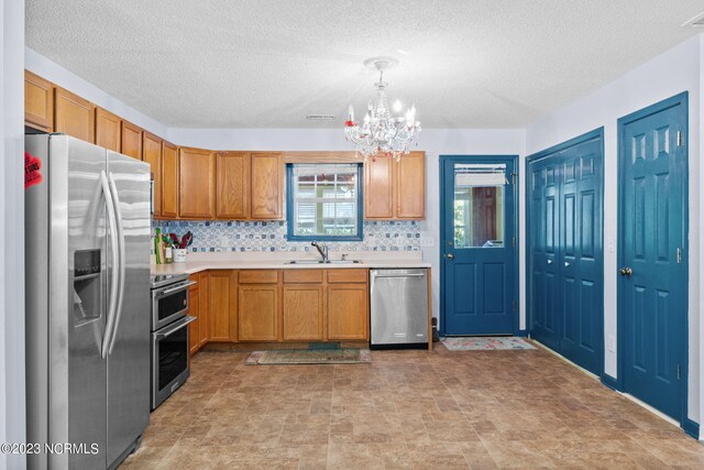 kitchen with appliances with stainless steel finishes, sink, a chandelier, and light tile floors