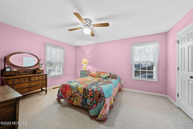 carpeted bedroom with ceiling fan and a textured ceiling