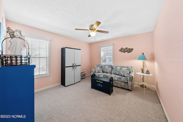 living room with ceiling fan, light carpet, and a textured ceiling