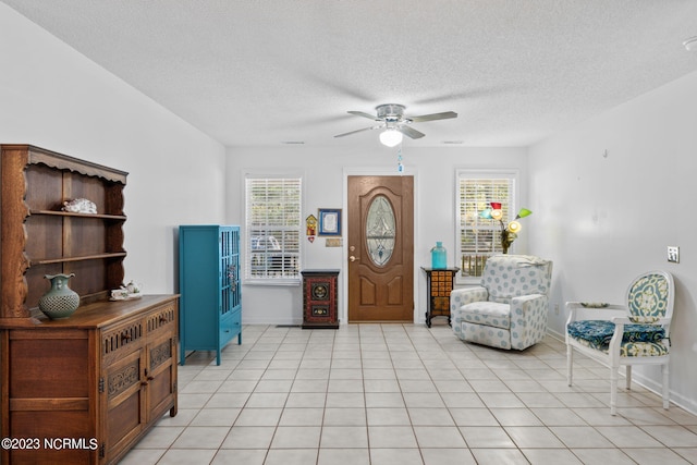 living area with ceiling fan, light tile flooring, and a textured ceiling