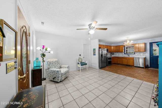 living room with sink, a textured ceiling, ceiling fan with notable chandelier, and light tile flooring