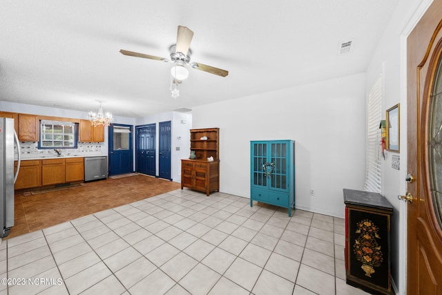 kitchen with sink, light tile floors, appliances with stainless steel finishes, tasteful backsplash, and ceiling fan with notable chandelier