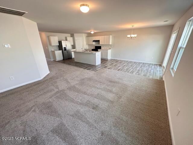 spare room with an inviting chandelier and dark carpet