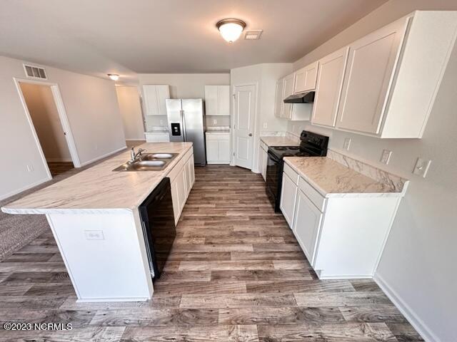 kitchen with dark hardwood / wood-style flooring, white cabinetry, black appliances, a kitchen island with sink, and sink