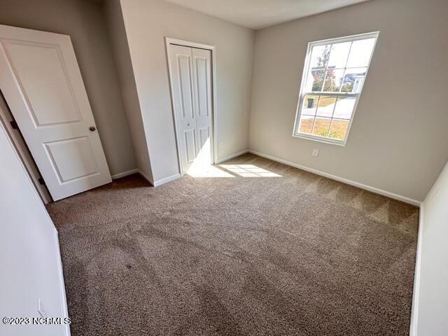 unfurnished bedroom featuring a closet and dark carpet