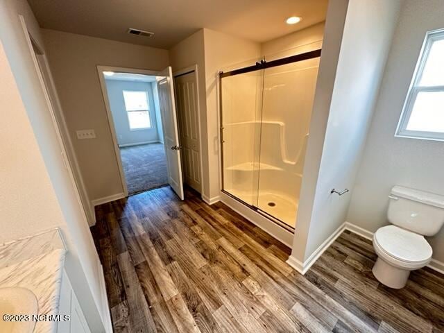 bathroom with walk in shower, toilet, a healthy amount of sunlight, and hardwood / wood-style flooring