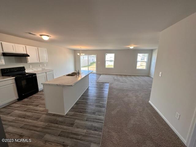 kitchen featuring a chandelier, black range with electric stovetop, dark wood-type flooring, white cabinetry, and sink