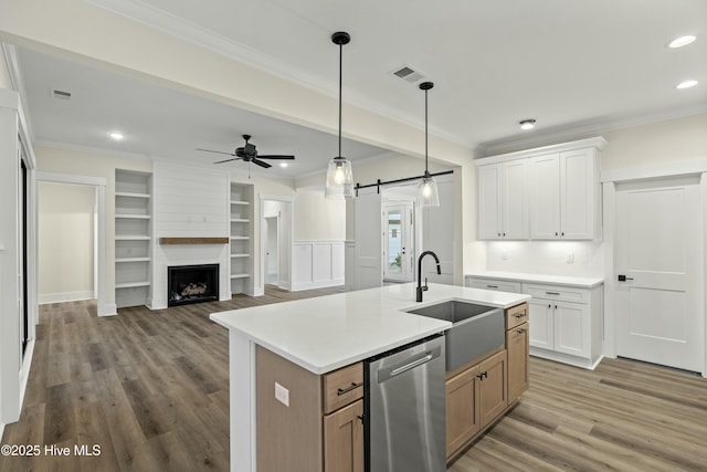 kitchen featuring ornamental molding, a barn door, a sink, and stainless steel dishwasher