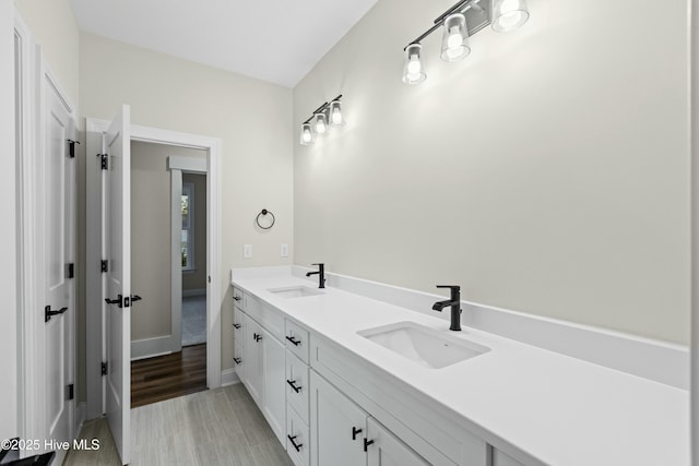 bathroom featuring double vanity, a sink, and baseboards