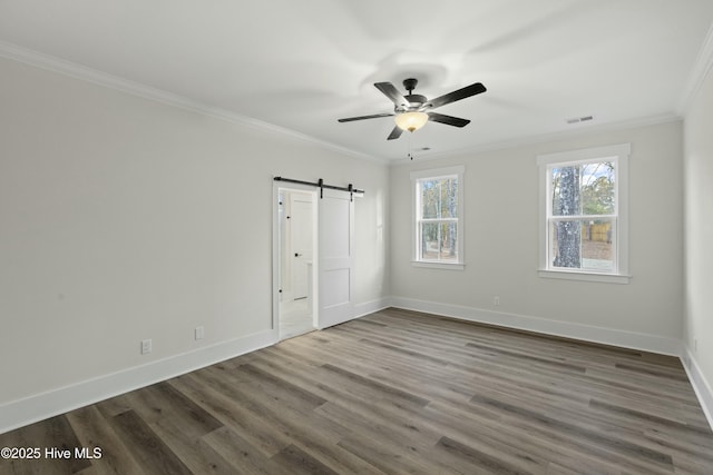 unfurnished room featuring ornamental molding, a barn door, wood finished floors, and visible vents