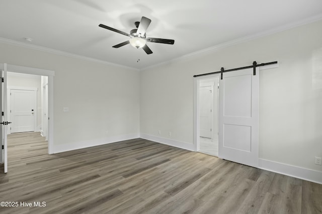 interior space with ornamental molding, a barn door, and wood finished floors