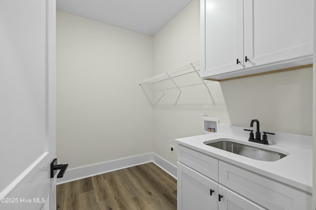 clothes washing area featuring washer hookup, dark wood finished floors, cabinet space, a sink, and baseboards