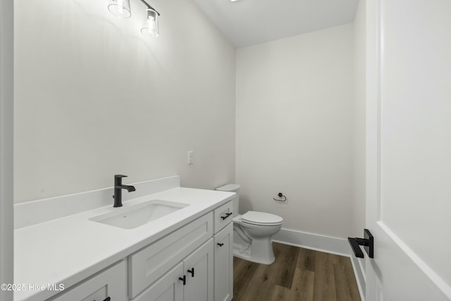 half bathroom featuring baseboards, vanity, toilet, and wood finished floors