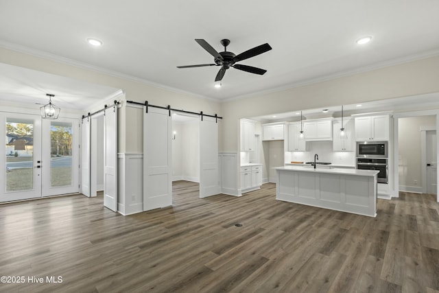 kitchen with a barn door, oven, a sink, white cabinets, and built in microwave