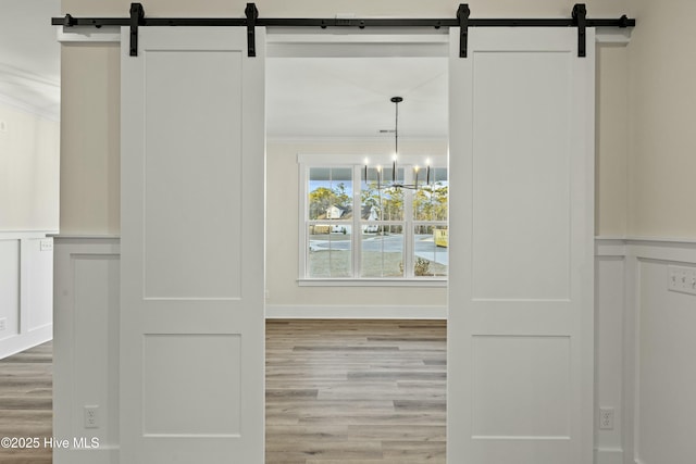 interior space featuring a barn door, crown molding, and wood finished floors