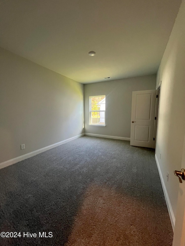 spare room featuring dark carpet