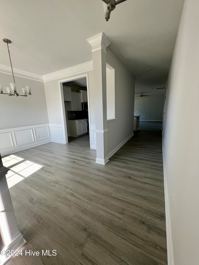 interior space with ceiling fan with notable chandelier, crown molding, dark wood-type flooring, and decorative columns