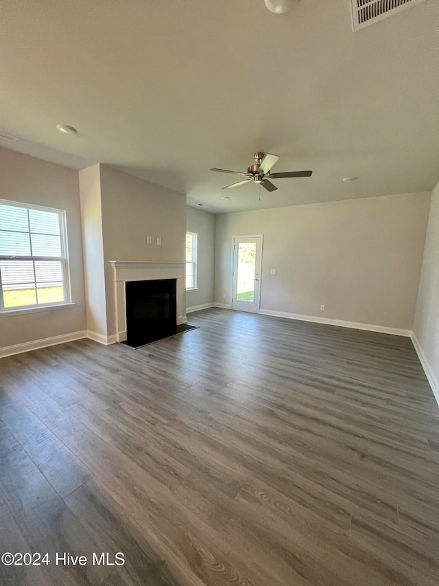 unfurnished living room with dark hardwood / wood-style flooring and ceiling fan